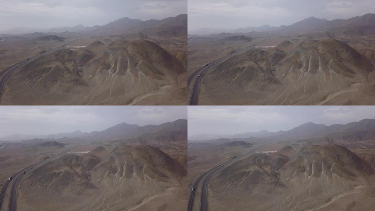 无人驾驶飞机在沙漠中的一座大山的空中视图，旁边是汽车的机智
