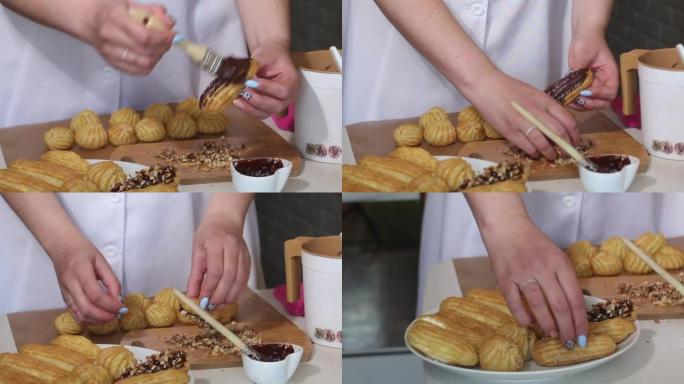 一个女人用巧克力涂抹蛋糕，然后将其浸入坚果中。自制奶油泡芙放在盘子里。糕点。中等计划