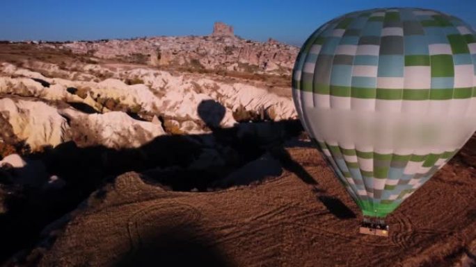 热气球的鸟瞰图，游客乘坐篮子降落在卡帕多西亚山谷的地面上