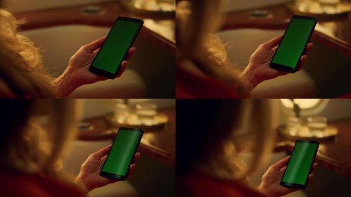 特写手握绿屏手机。使用样机的中年妇女