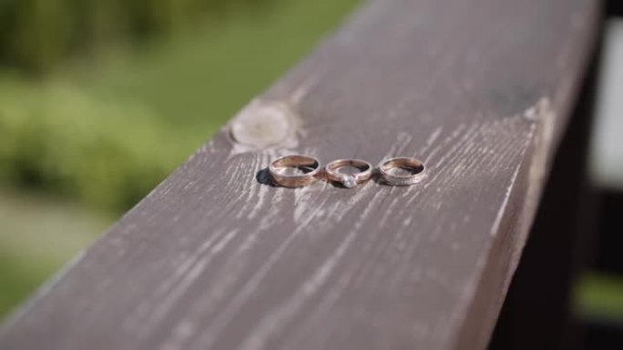 三个不同大小的金戒指躺在油漆和磨损的木板上。