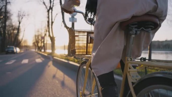 戴围巾长镰刀的女人在路上骑黄色自行车