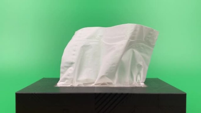 慢动作，一个人的手从隔离在绿色背景上的纸巾纸盒中拉出一块纸巾。