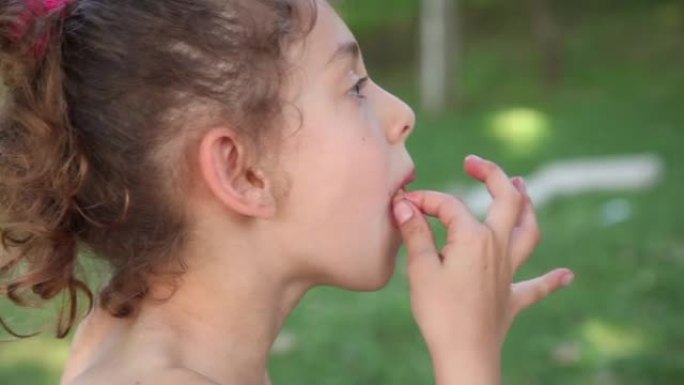 一个小女孩在公园吃草莓的侧视图