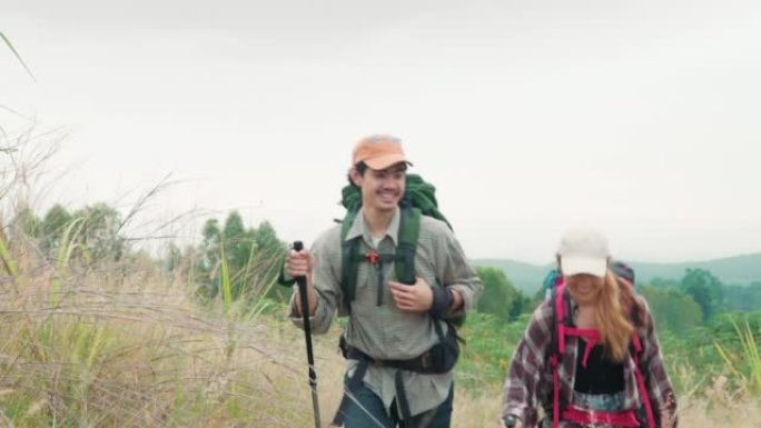 快乐的年轻夫妇徒步旅行者走过一片干燥的草地。年轻的男人和女人一起享受美好的时光。