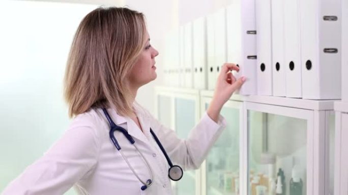 女医生或护士选择并取出带有文件的白色文件夹