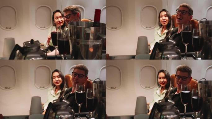 幸福的夫妇在飞机上向空姐订购香槟，航空服务理念
