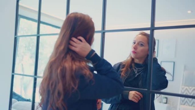 严肃的女性移动头发照镜子的慢动作，自信的年轻成年人在飞行前站在酒店房间里照镜子