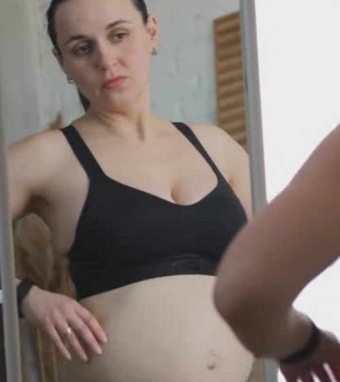 孕妇在镜子里看着腹部脂肪