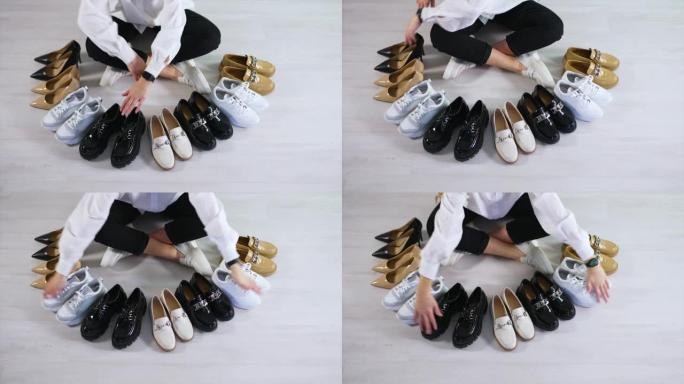 坐在地板上的女人数着她面前的那双鞋子。各种鞋类展示。从顶部看。