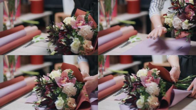 女花店制作花束，用包装纸包装插花，在花店工作。花卉商店的高加索专业人士。花卉设计、花艺、手工制作、小