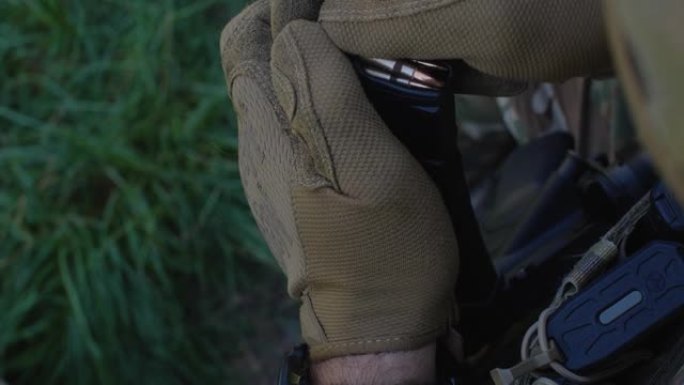 身着迷彩制服的士兵为军事演习或战斗做准备。极端近距离的军人的手向机枪充子弹。乌克兰军队，战争