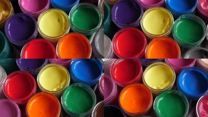 将水粉画颜料放在罐子里明亮的颜色特写。塑料罐上的多色水粉旋转套装。旋转多色背景。多色油漆的背景。创意