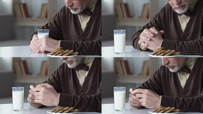 悲伤的老人坐在餐桌旁拒绝喝牛奶，在养老院不开心