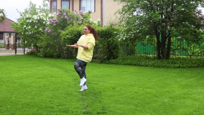 卷曲丰满的胖女人，穿着黄色运动衫，体重过重，在公园里做运动、跳跃、高膝盖水龙头。减肥
