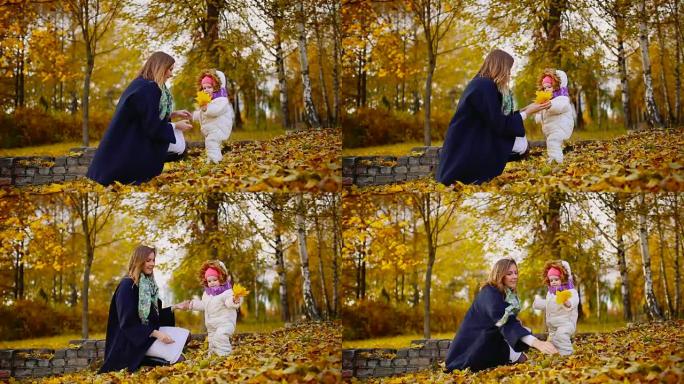 秋天，当黄色的叶子围绕着妈妈和女孩玩枫叶，笑着微笑。妈妈在秋天拥抱和我女儿玩耍。波克和阳光