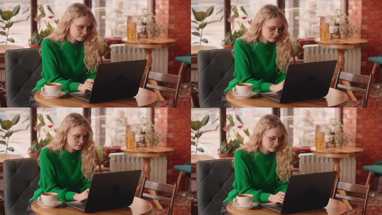 美丽的年轻女子学生在咖啡馆远程工作或学习，在笔记本电脑上输入信息