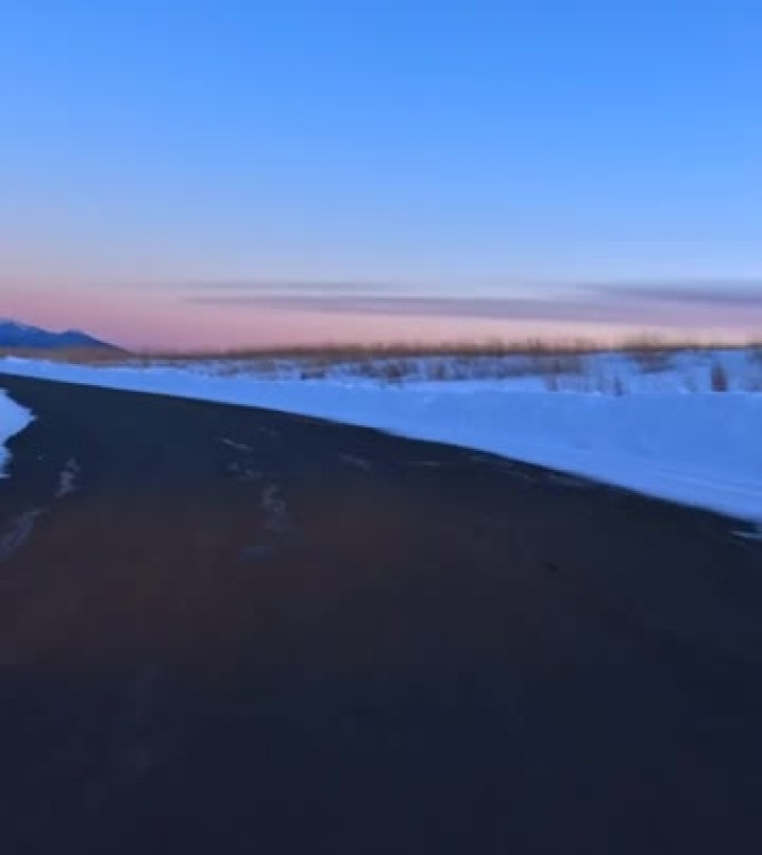 黄昏时在雪山路上行驶。