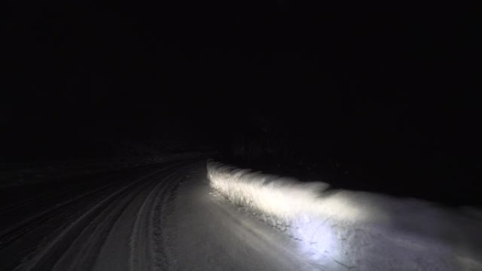 晚上在森林的雪路上开车。掉头