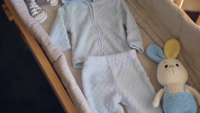 为分娩准备的手工木制婴儿床，蓝色衣服，鞋子，针织兔子玩具和婴儿床内的超声波性别图片，期待男婴到来的概
