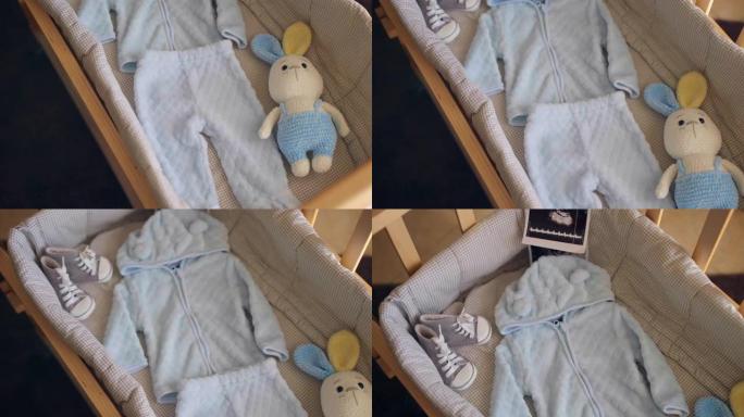 为分娩准备的手工木制婴儿床，蓝色衣服，鞋子，针织兔子玩具和婴儿床内的超声波性别图片，期待男婴到来的概