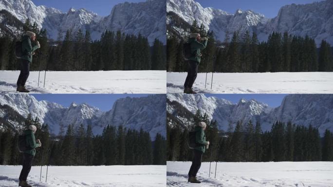 男子在山上滑雪旅行时从罐子里喝酒