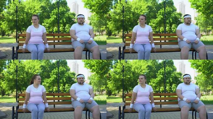两个可爱的肥胖人谦虚地坐在长凳上，太害羞了，无法结识