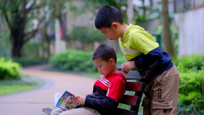 两个小朋友在公园长椅看漫画书