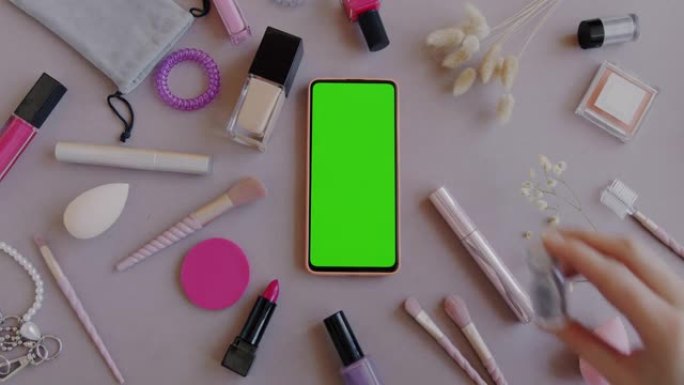 平铺女性配件和化妆工具，带绿色屏幕色度键智能手机，背景为灰色
