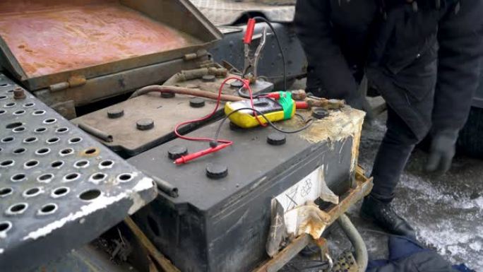 机械师的手用电池充电器给一辆没电的卡车电池充电。