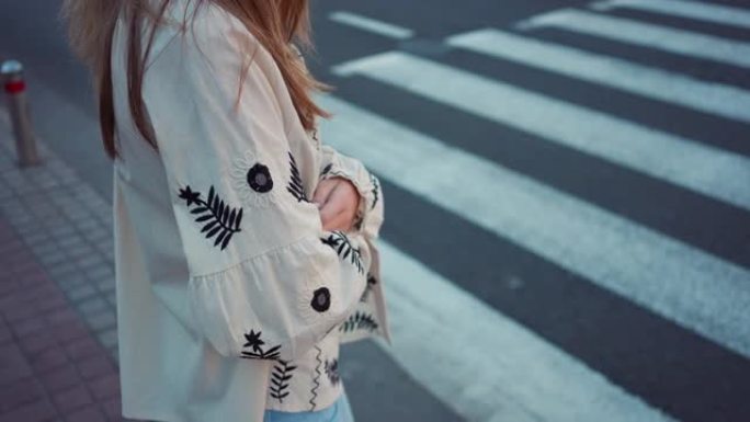 侧视图无法辨认的少女穿着刺绣乌克兰衬衫站在户外人行横道。在城市等待过马路的少年。慢动作。
