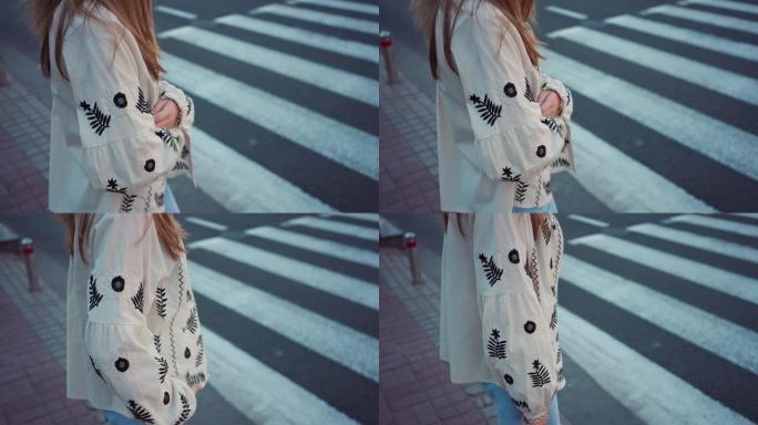 侧视图无法辨认的少女穿着刺绣乌克兰衬衫站在户外人行横道。在城市等待过马路的少年。慢动作。