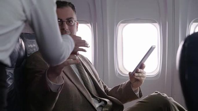 在飞机上使用数字平板电脑的商人
