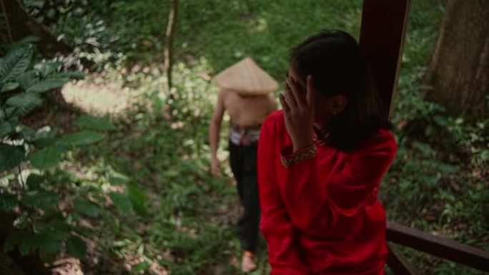 亚洲男子戴竹帽偷偷摸摸穿红色连衣裙的女子