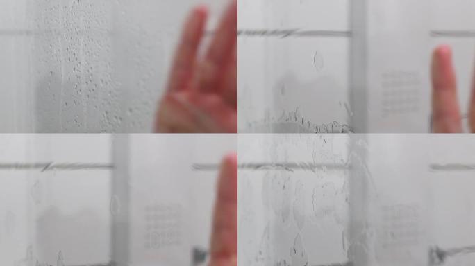 消除雾气: 一个女人的手清理玻璃淋浴门的特写镜头