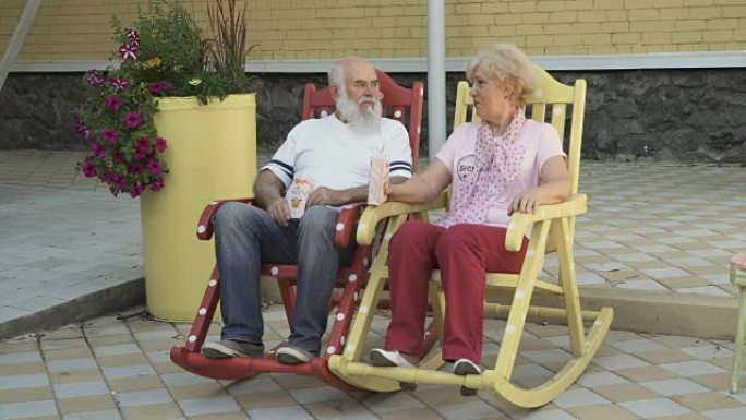 老人和老妇人坐在摇椅上吃爆米花