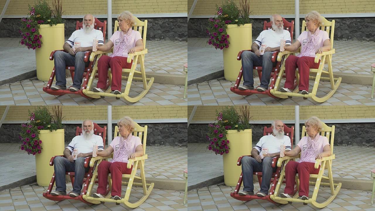 老人和老妇人坐在摇椅上吃爆米花