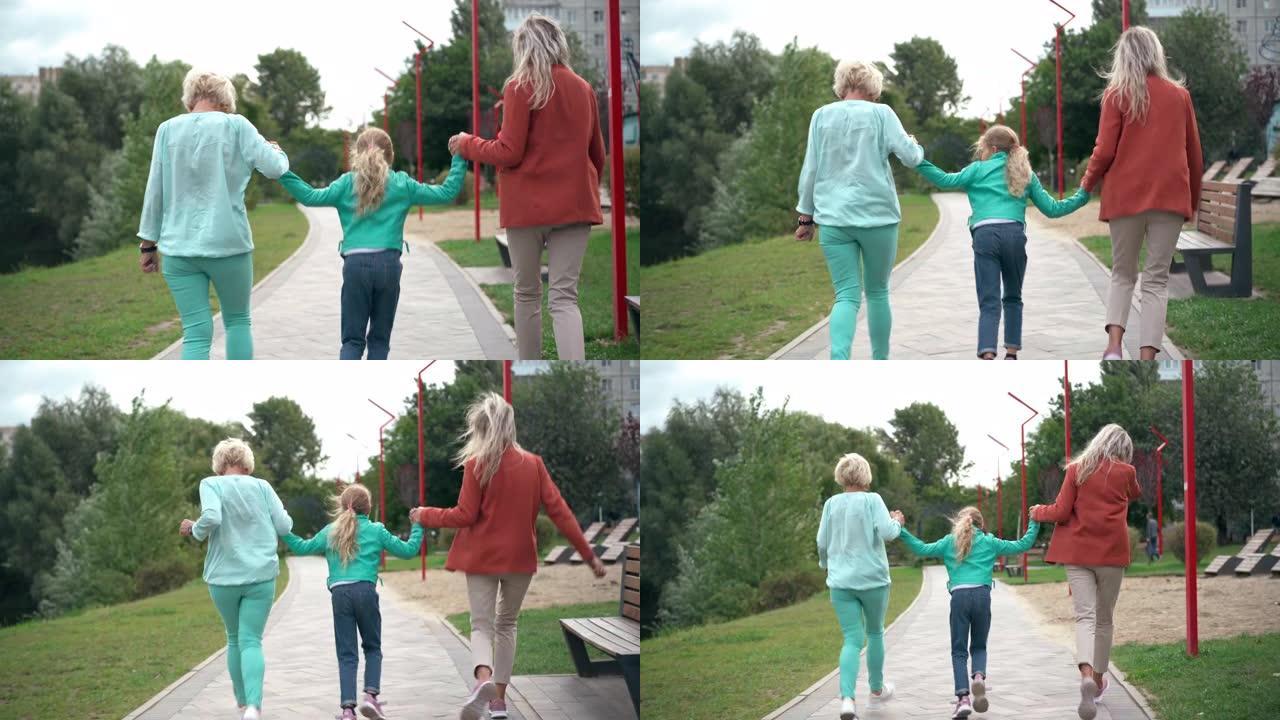 后视图开朗的女孩与祖母和母亲牵着手在小巷上奔跑。宽镜头快乐无忧无虑快乐的高加索女儿孙女与多代家庭玩得