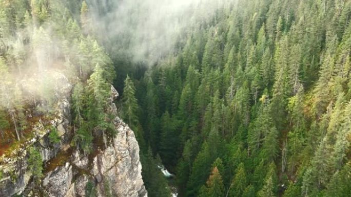 空中翻盘穿过薄雾笼罩的峡谷，河流在下面流动
