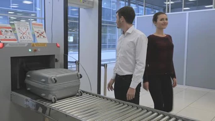 男人和女人在机场的x射线扫描仪中扫描时等待行李