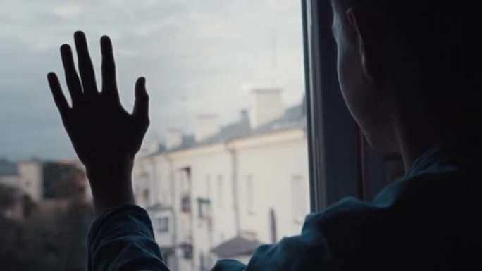 男孩站在窗边，看着房子的屋顶，童年的经历，电影般的镜头