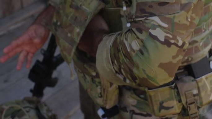 一名穿着迷彩制服的难以辨认的男性士兵的手特写，他正准备进行军事演习或战斗。军人紧固他的防弹衣。乌俄战