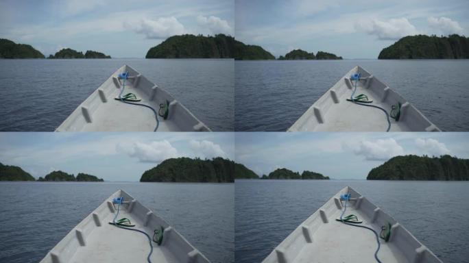 一艘小船在热带水域的正面视图，背景是岛屿