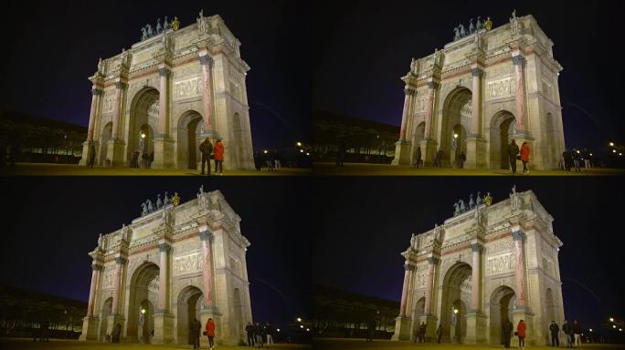 许多人在法国巴黎夜晚的卡鲁塞尔广场 (Place du Carrousel) 的凯旋门上行走