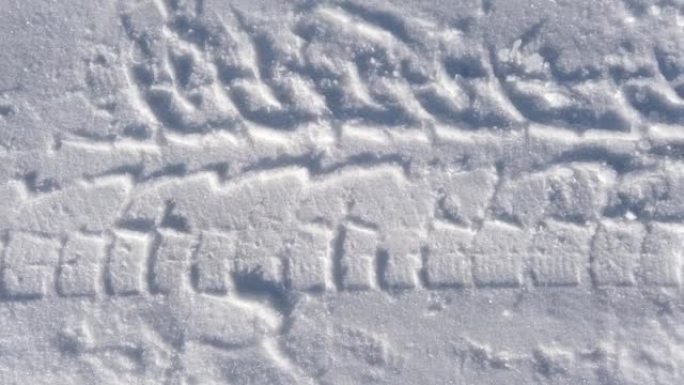 雪地里汽车轮胎胎面的足迹。雪道纹理。各种想法的背景。阳光硬阴影背景。产品展示，广告的最小模型。潮流效