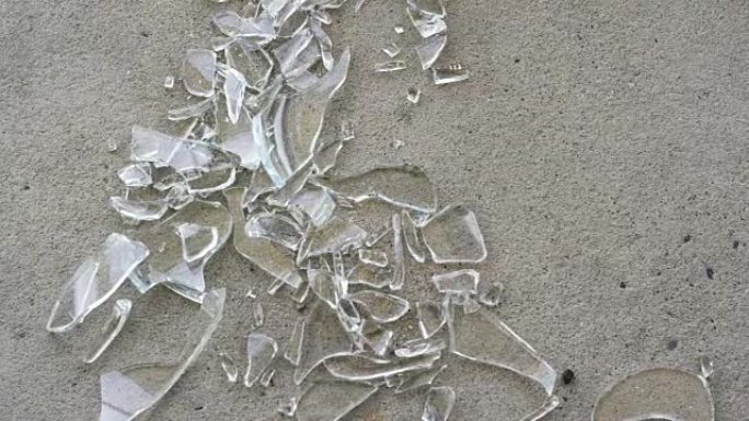 一名妇女用扫帚扫过人行道上的碎玻璃