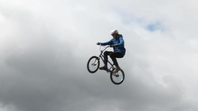 BMX自行车男子跳高多云背景慢动作