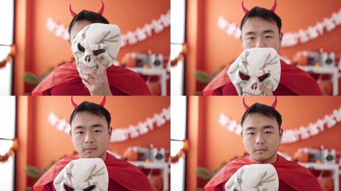 穿着魔鬼服装的中国年轻人在家中手持骷髅面具