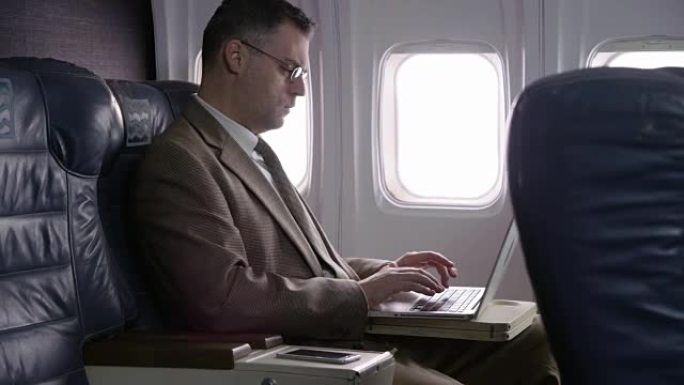 商人在飞机上使用笔记本电脑