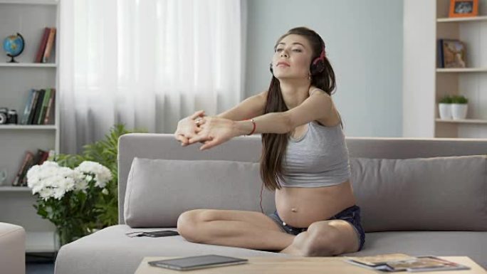 孕妇坐在耳机里锻炼，怀孕瑜伽音频指南